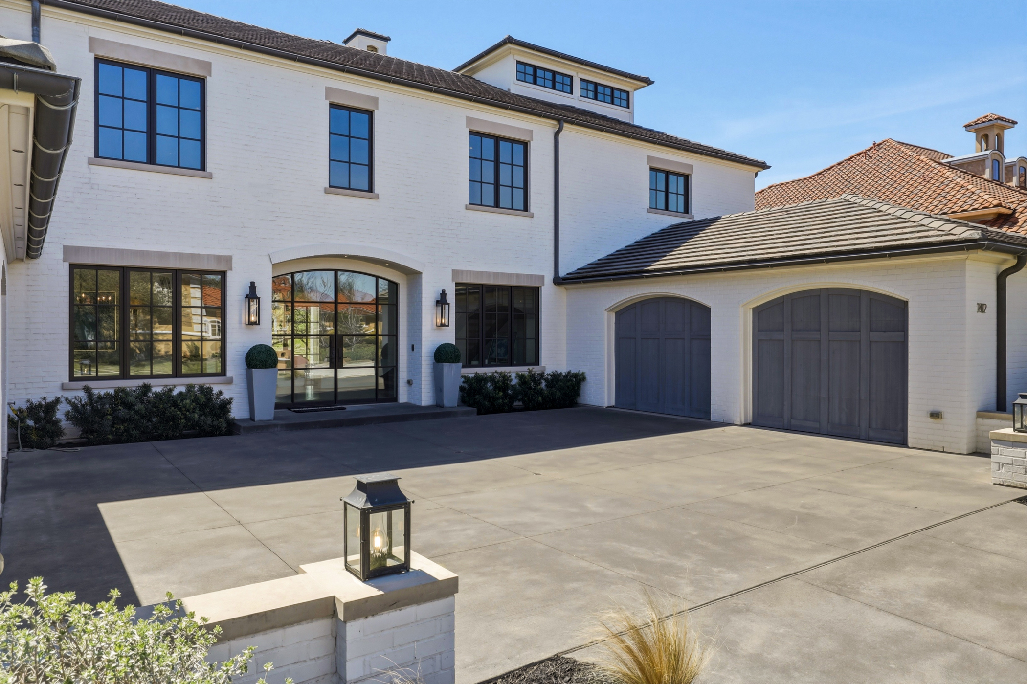 White brick contemporary home with arched windows listed by The Assaad Group